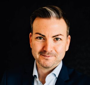 Man in suit and shirt smiles