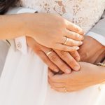 Mann umarmt Frau von hinten Hände mit Ringen zu sehen