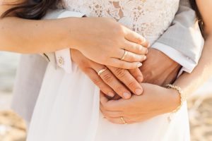 Mann umarmt Frau von hinten Hände mit Ringen zu sehen