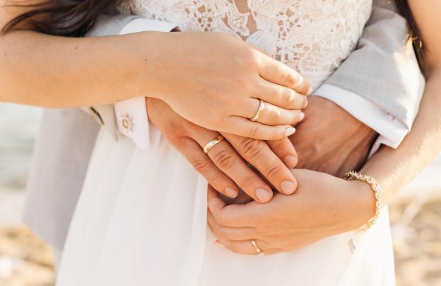 Mann umarmt Frau von hinten Hände mit Ringen zu sehen