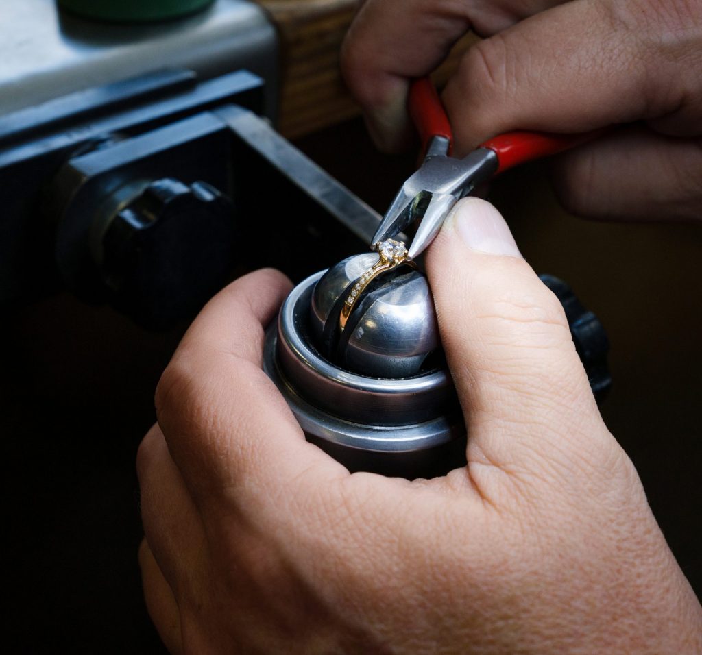 Goldschmied befestigt Diamanten an Ring
