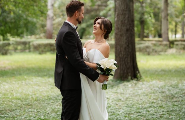 Braut und Bräutigam in Hochzeitskleidung lachend im Park