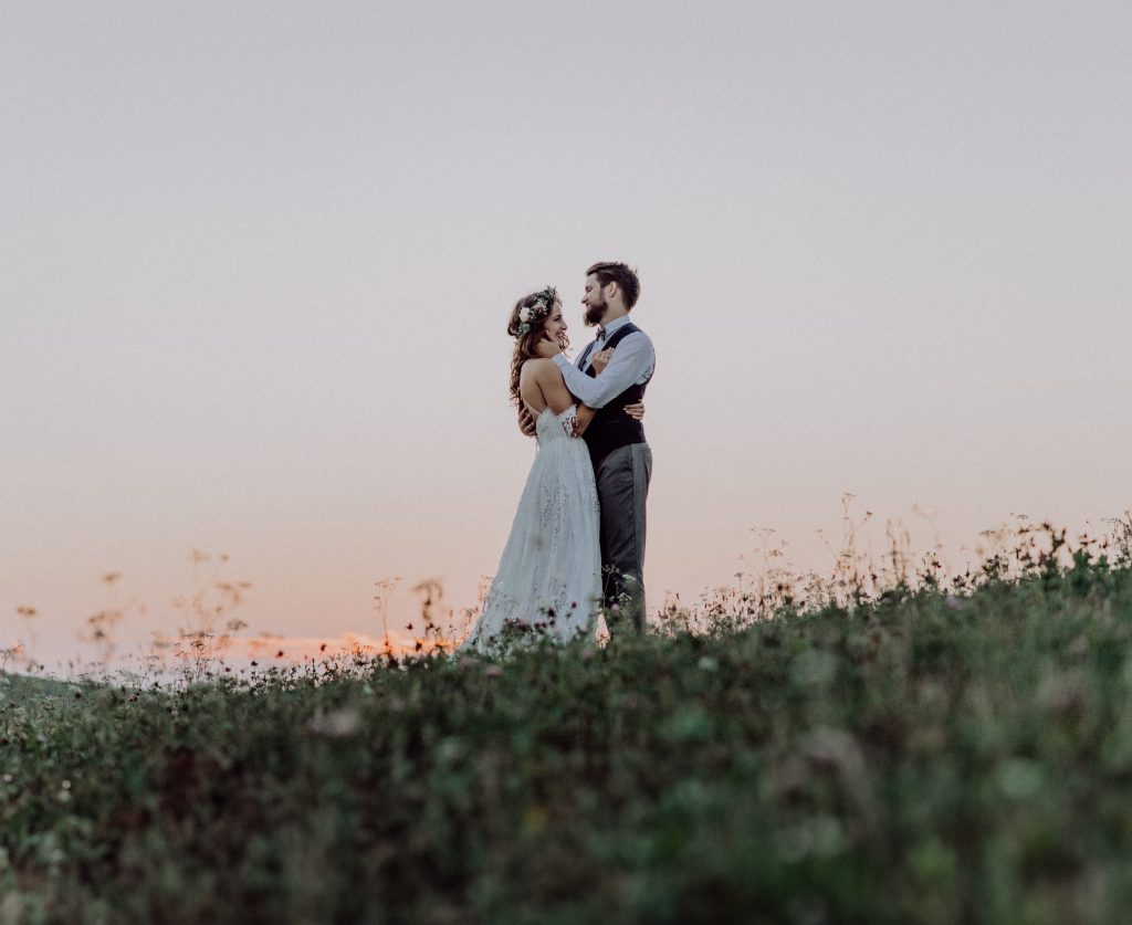 Paar in Hochzeitskleidung umarmt sich in Feld