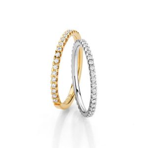 Two wedding rings in yellow gold and white gold with a continuous row of diamonds, made in Germany by Fischer Trauringe