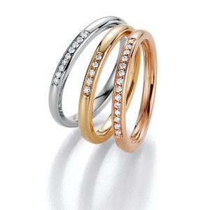 Three wedding rings in white gold, apricot gold, and rose gold with diamond setting by Fischer Trauringe